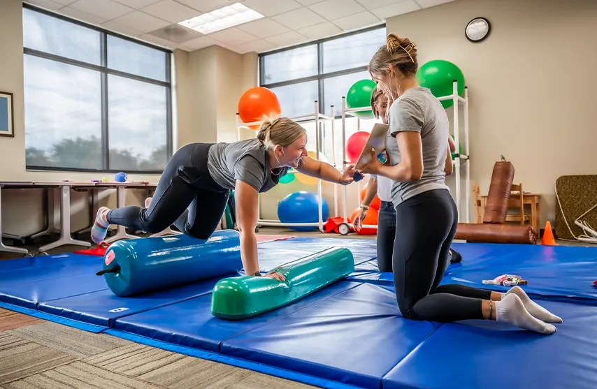 Two students practice motor skills in a physical therapy class.